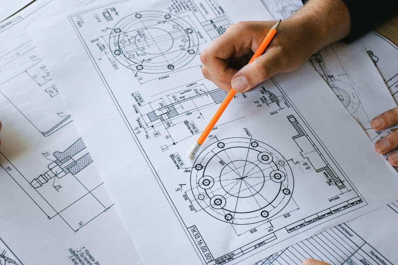 Engineers reviewing technical design drawings with a pencil