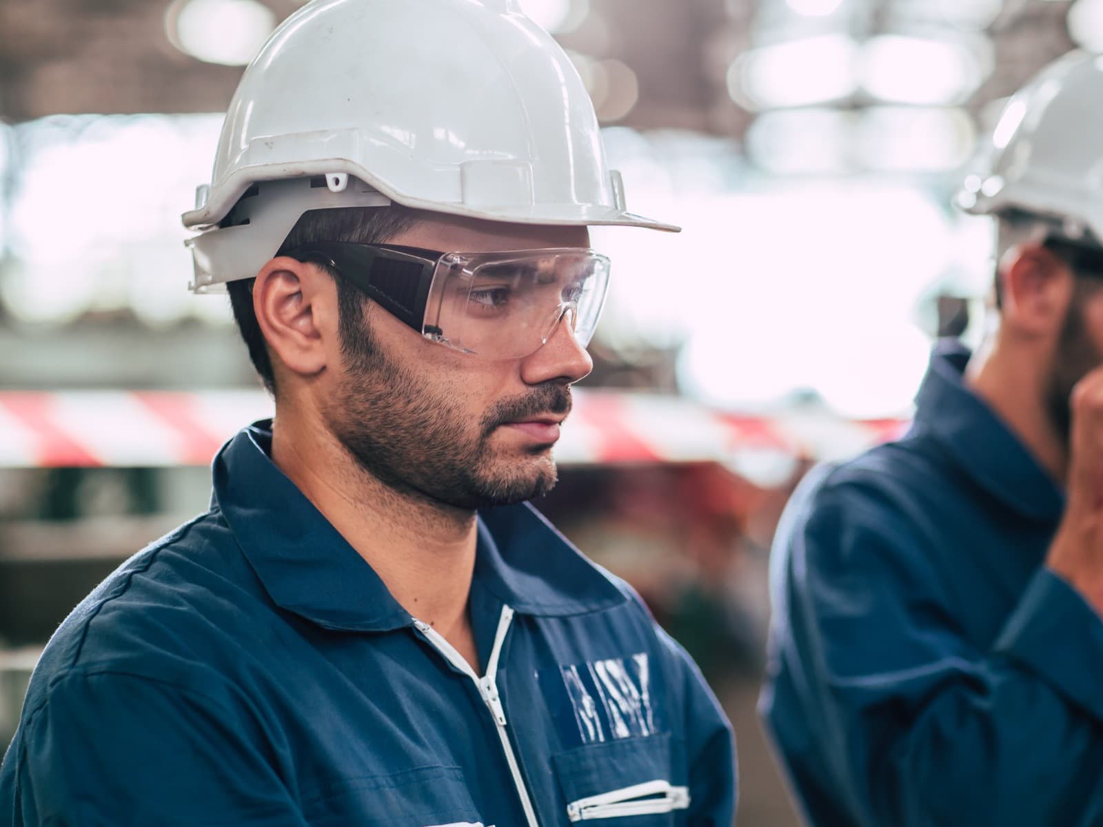 Engineer in a safety helmet and safety glasses on a factory floor