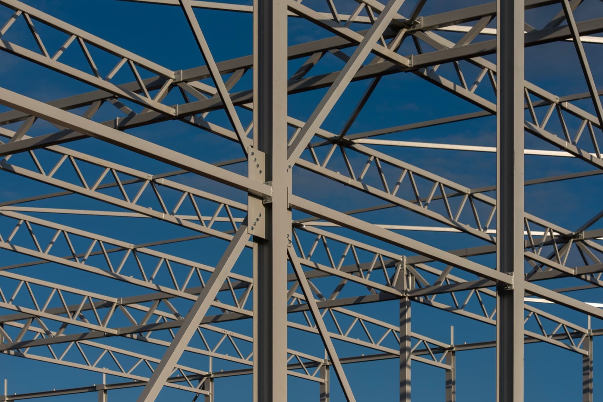 Steel roof trusses of an industrial building against a blue sky